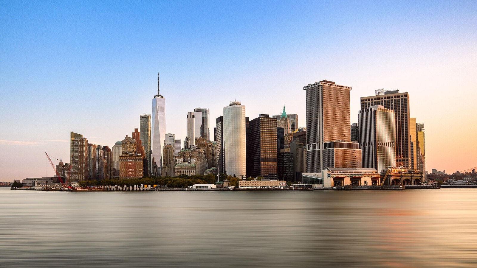 The Lower Manhattan skyline at sunrise, seen across the harbor, One World Trade Center at the left